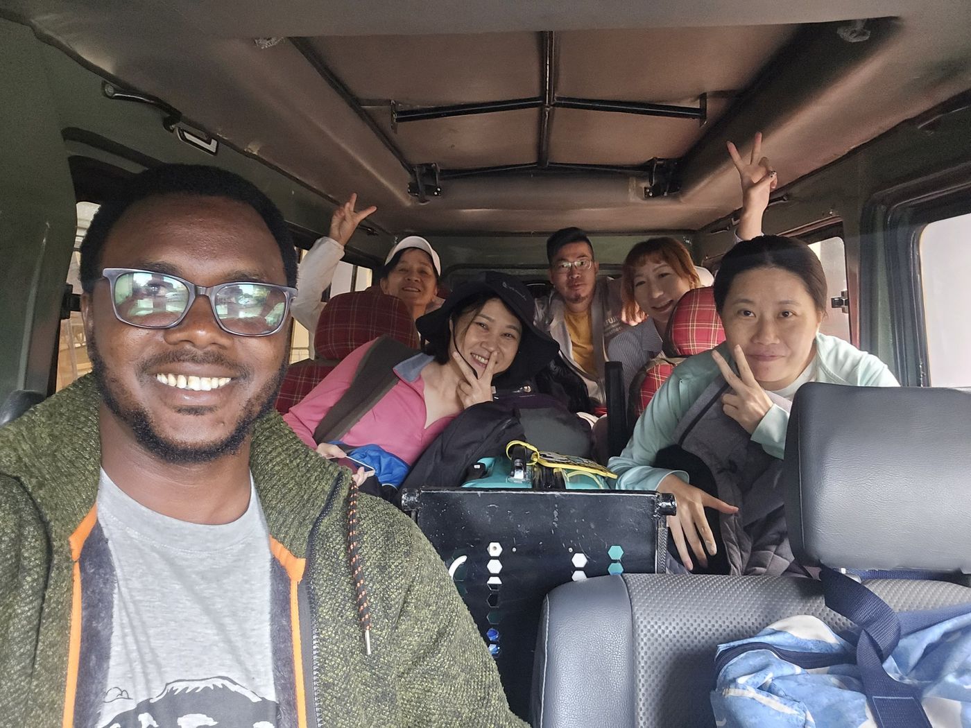 Sylvester with a group of smiling guests inside the Land Cruiser