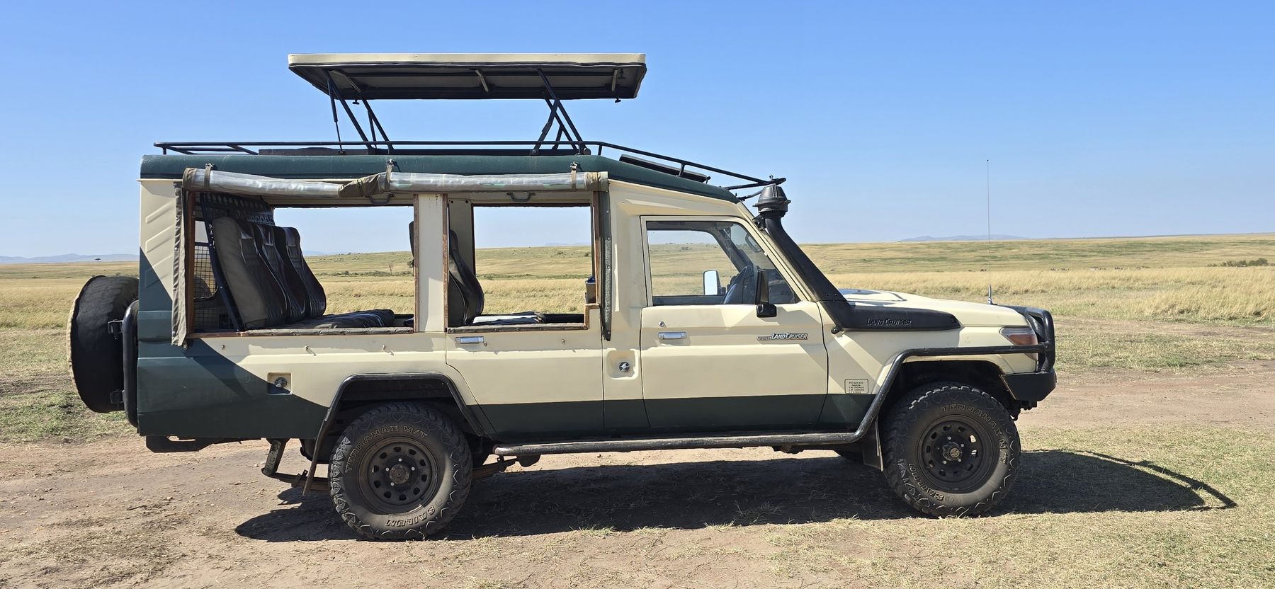 Sylvester's Toyota Land Cruiser with its pop-up roof raised, on the open plains