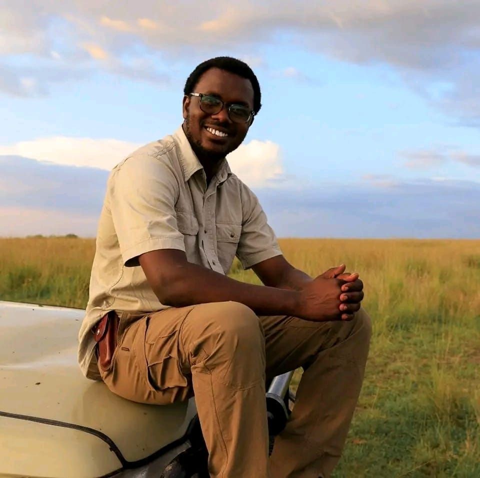 Sylvester sitting on the bonnet of his Land Cruiser in the Mara