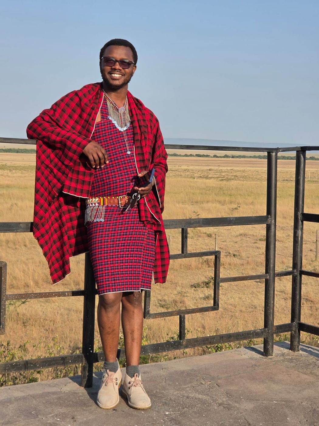 Sylvester in a red Maasai shuka at a viewpoint above the Mara plains